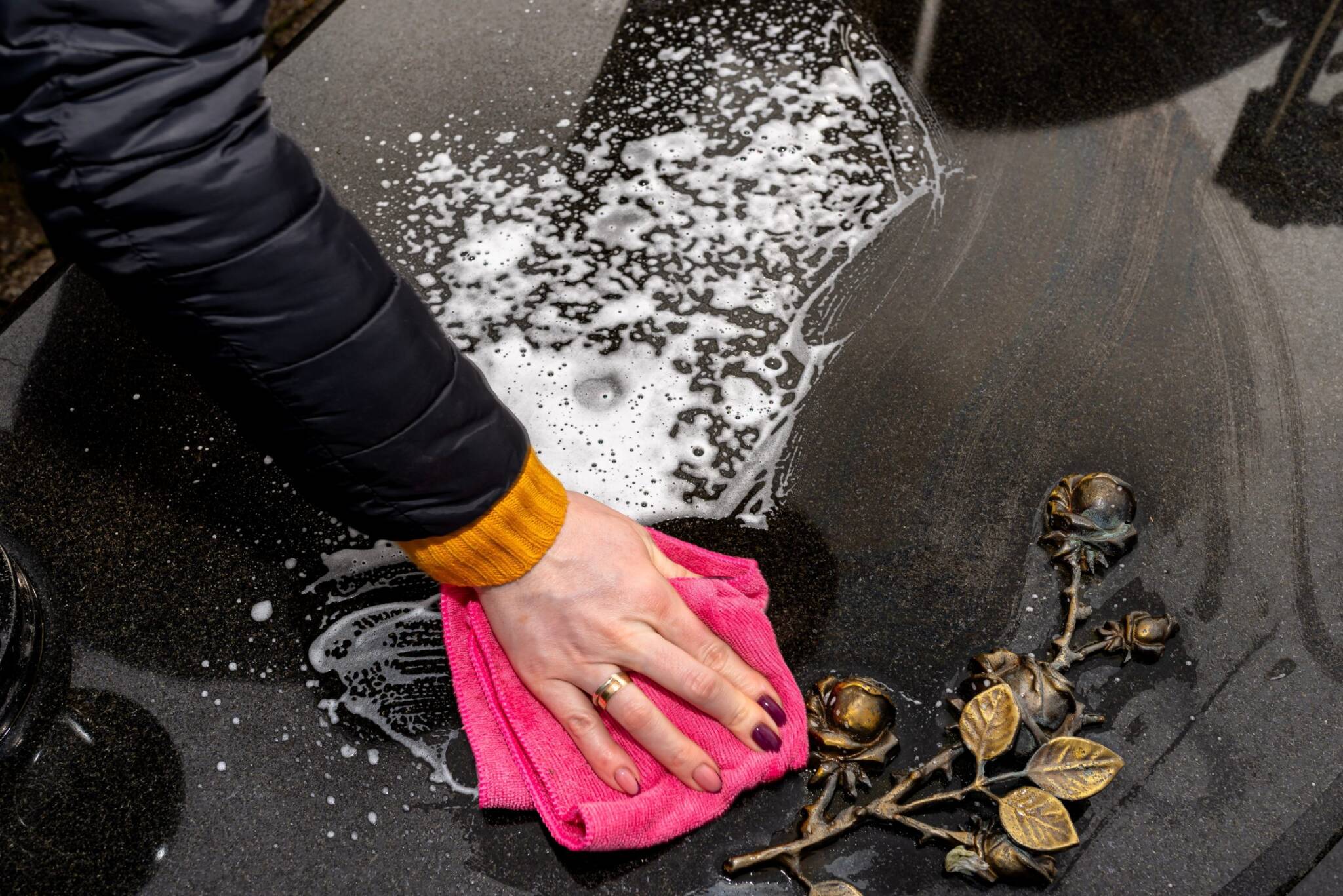 Cleaning,a,black,tombstone,with,a,cloth,and,water,,female